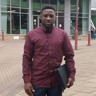 A student standing in front of the main entrance to the Richmond Building at the University of Bradford