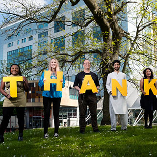 8 students each holding a letter of the alphabet. Together they spell 'Thank you'