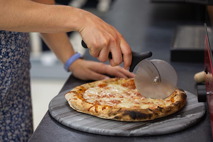 A student cutting a pizza.