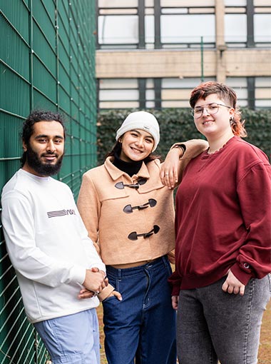 Three students smiling at the camera.