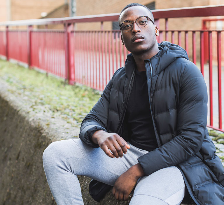 A student sitting on outdoor steps and looking at the camera