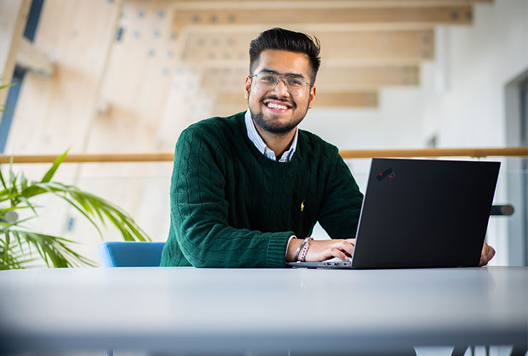 A postgraduate student sat at a desk with their laptop.