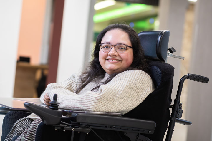 A student sitting in a wheelchair and smiling at the camera