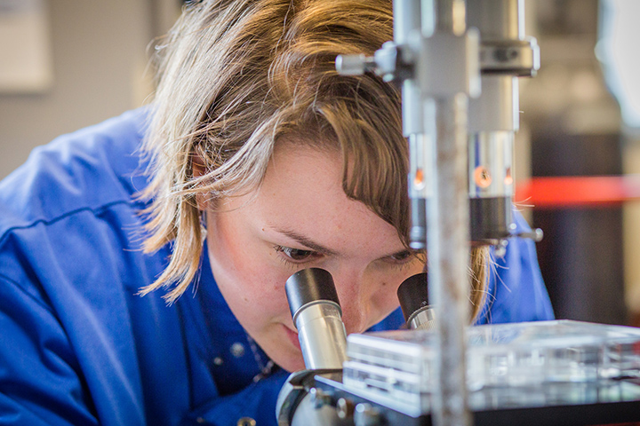 An image of technician looking through a microscope