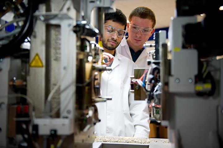 An image of a student being shown how to use equipment by a technician