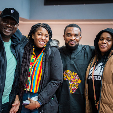 Four black students smiling at a One World Week event in Student Central