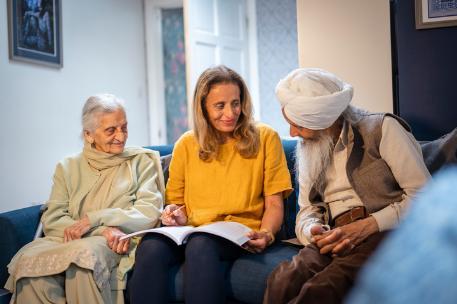 Three family members sitting next to eachother. The person in the middle is holding a book and a pen.