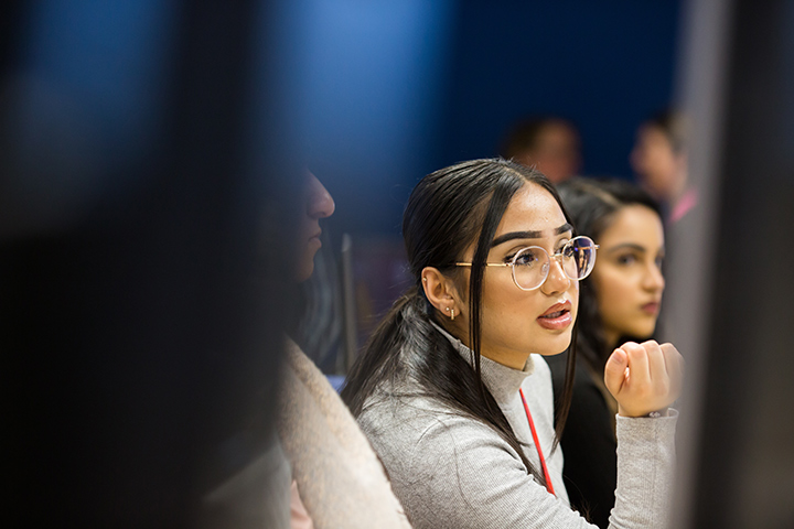 Student wearing glasses looking at a computer