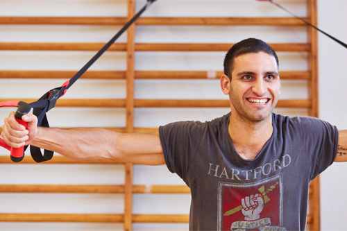 A smiling student pulling strength bands in our physiotherapy suite.