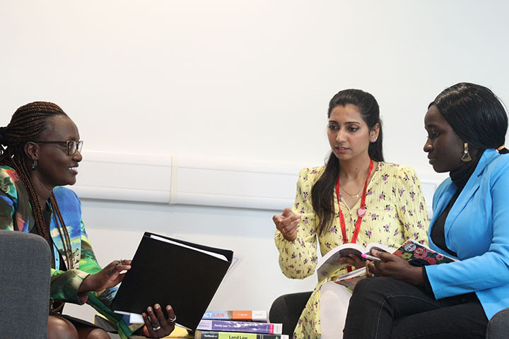 Three people sitting around an office table having a discussion.