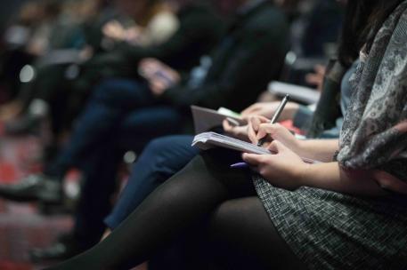 Close up of people taking notes at seminar meeting