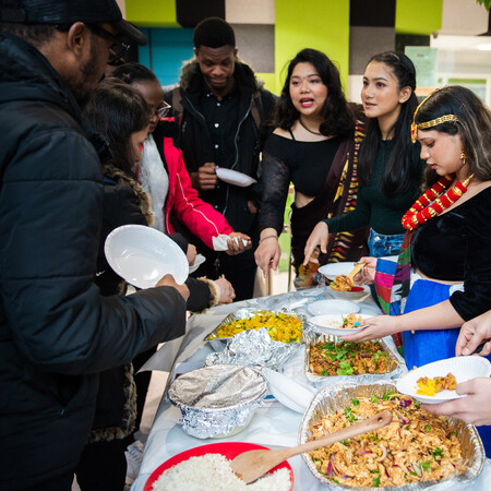 Students dishing out food onto their plates from a buffet table.