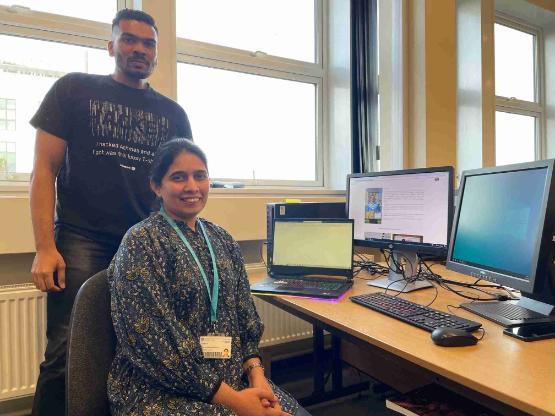 Student stood up and staff member sat down in front of computer