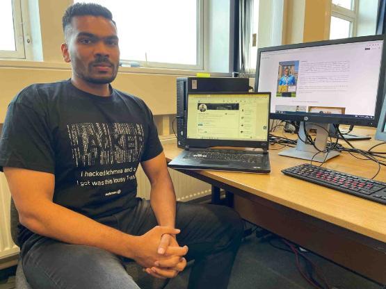 Student sat down at desk in front of a laptop and a computer at a desk