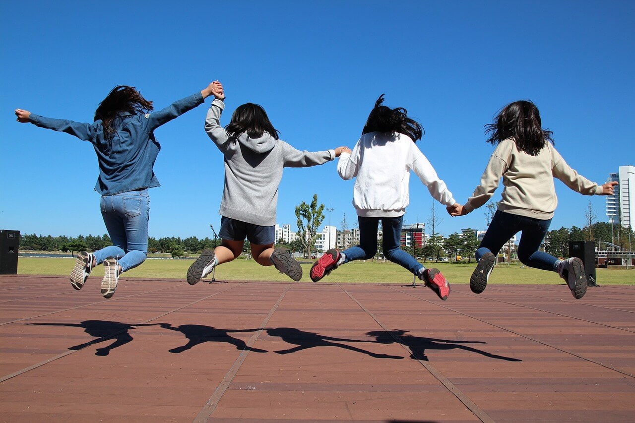 Four children jumping in the air in a playground