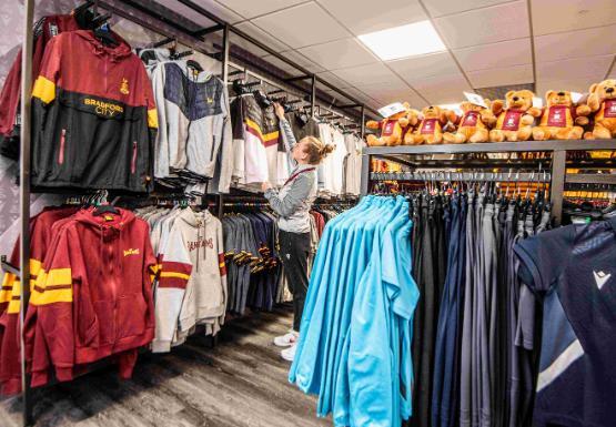 Person stood up putting shirts on display in store