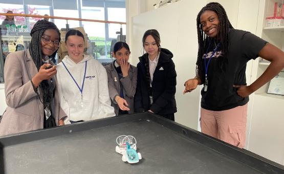 Five students stood around a table in a lab looking at a model car