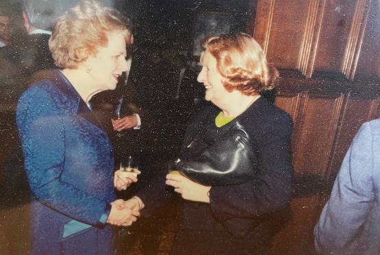 Two people stood up opposite each other in conversation at a formal event