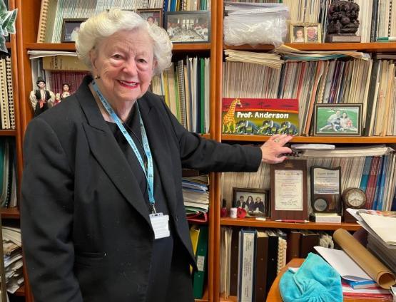 Academic stands up in front of shelves of books in their office