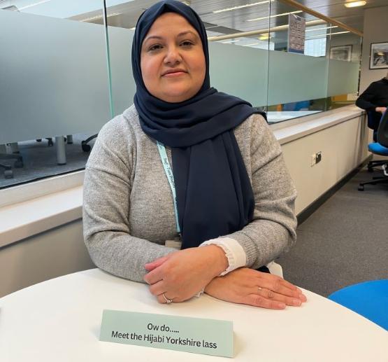 A staff member sits down behind small table in library