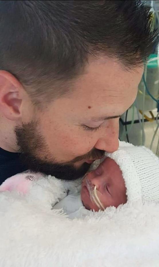 a person kissing a baby on their head while they are in hospital