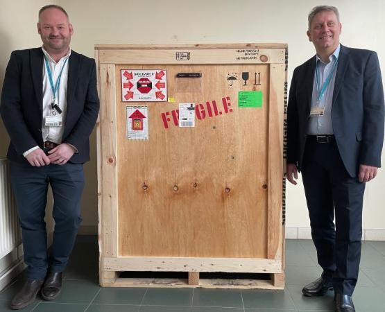 Two staff members stood either side of a giant wooden crate with fragile written on it