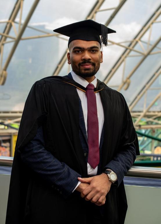 A student stood up wearing graduation gown at the university