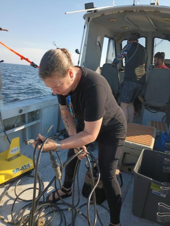 A university staff member leaning over while carrying out work on a boat