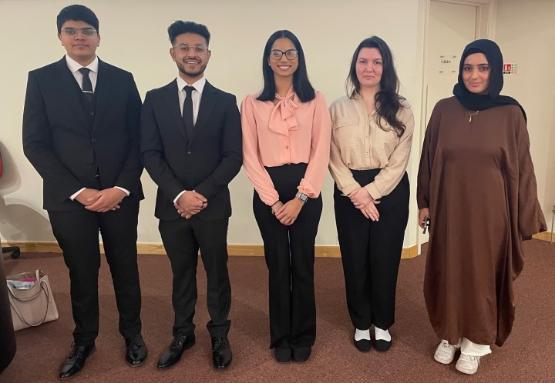 Five students in smart business-type dress stand up for photos