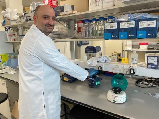 staff member wearing a white coat works inside a science lab