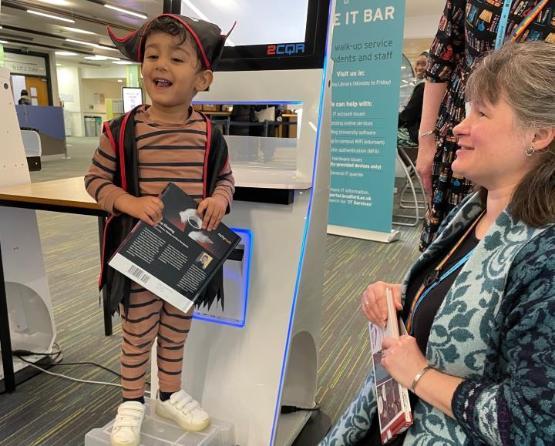 A youngster stood up holding a book inside a library