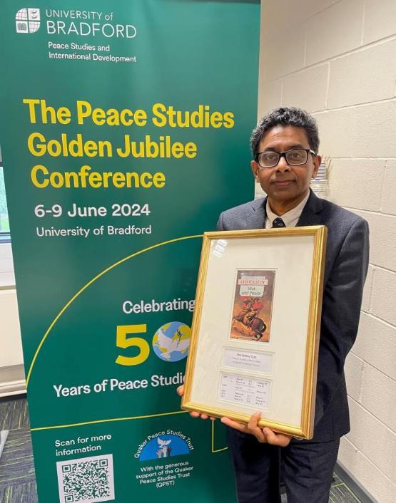 staff member holds up frame picture next to banner