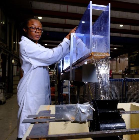 University student in white lab coat carries out experiment with water falling down