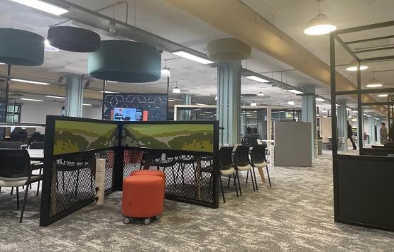 The inside of a large new library area with tables and chairs and an orange footstall