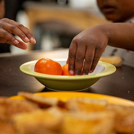 Square picture of children reaching for fruit at the nursery