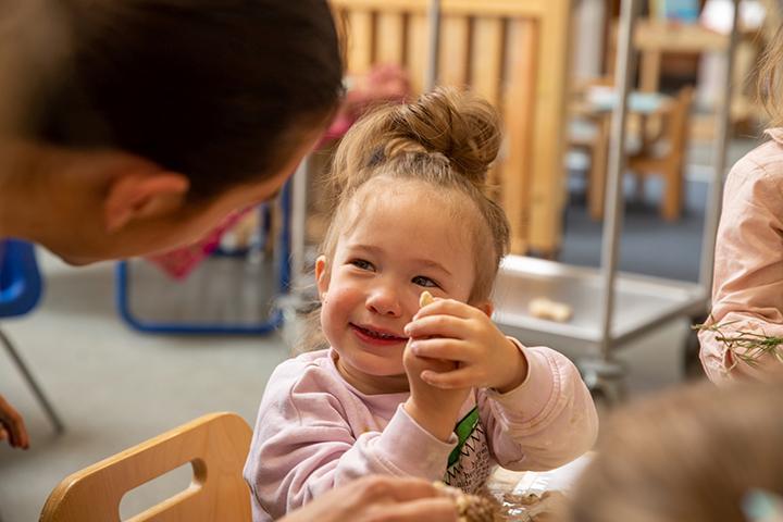 Nursery child smiling at her teacher 