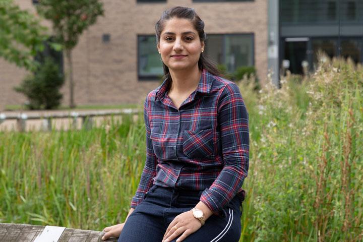 Shams Aliya sitting on a fence on campus