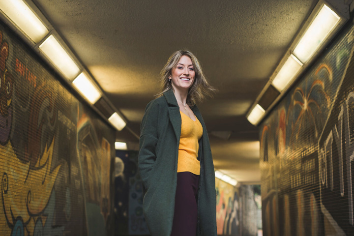 Jennifer Sjogren, an exchange student, smiling standing in a street art filled underpass in Bradford.