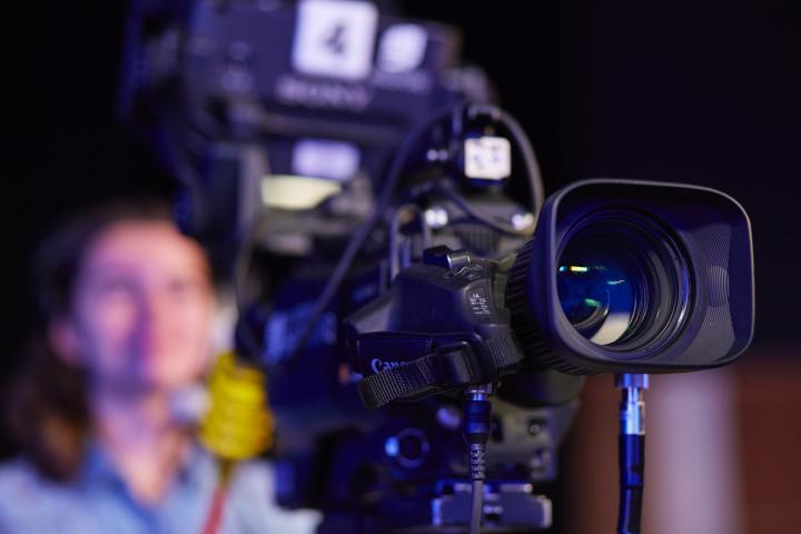 An image of a student using a camera within the Department of Media, Design and Technology.