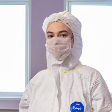 A student wearing forensics equipment looks towards the camera.