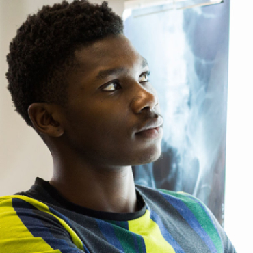 A student looks to the right of the camera with an x-ray scan behind them.