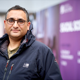 A person smiling at the camera at an open day event.