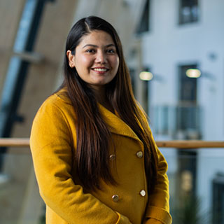 A student standing on a balcony smiling at the camera.