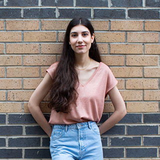 A person leaning casually against a brick wall.