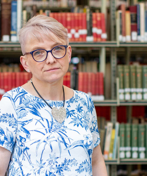 An Advanced Dementia Studies student smiling while standing in a library