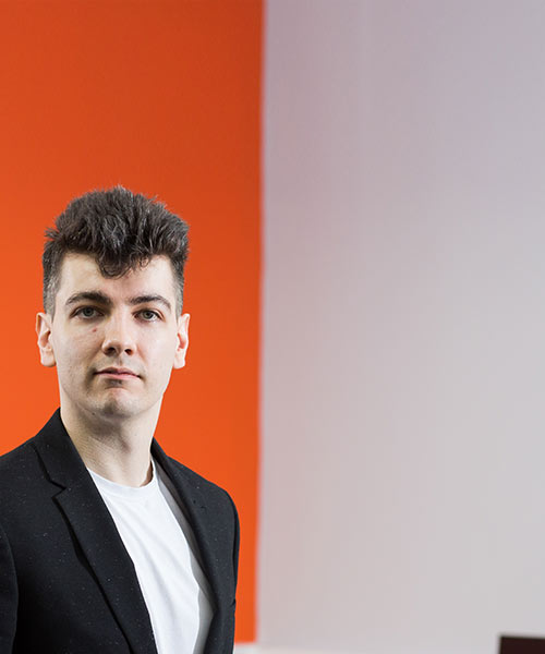 Student stood in front of a white and orange background